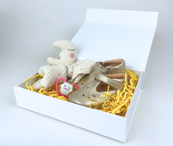 Weiße Geschenkbox mit Babyschuhen, Kuscheltier und gelbem Füllpapier