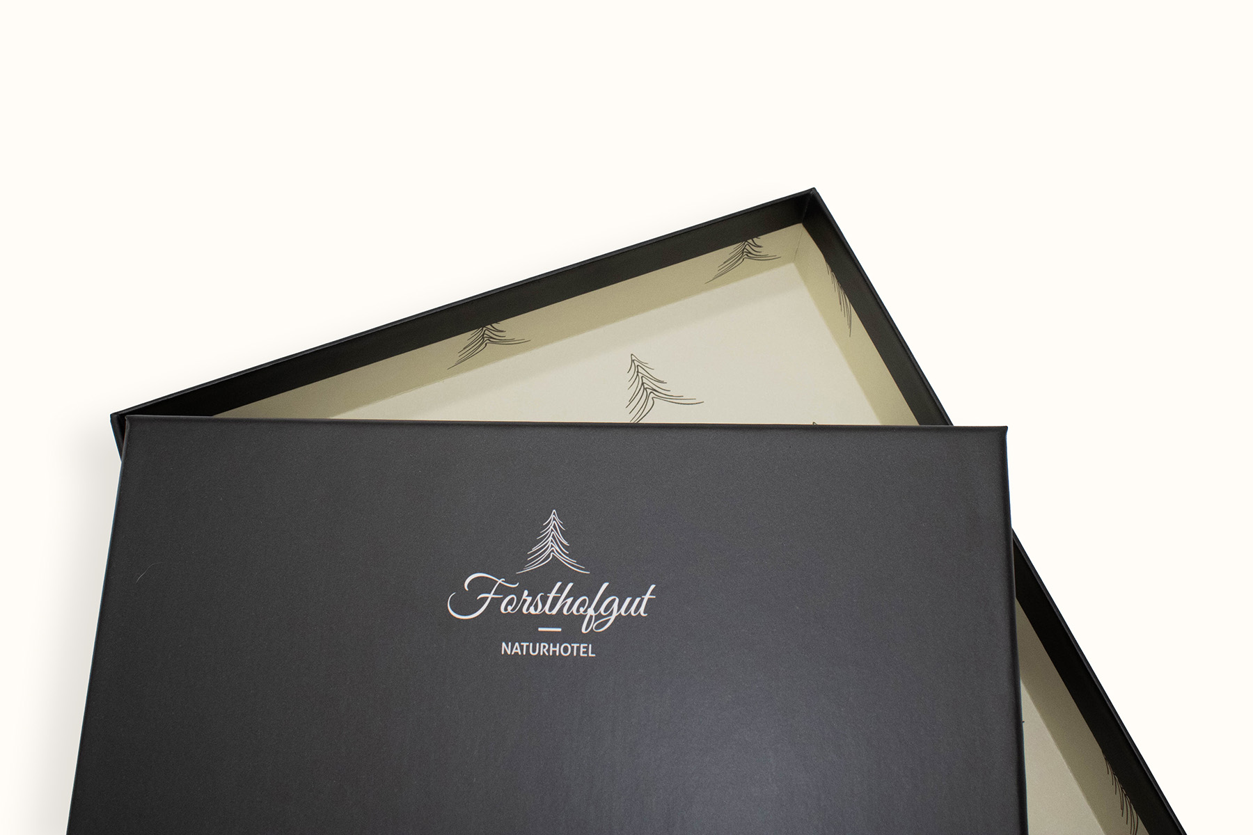 Schwarze Geschenkbox mit Logo des Naturhotels Forsthofgut und geöffnetem Deckel