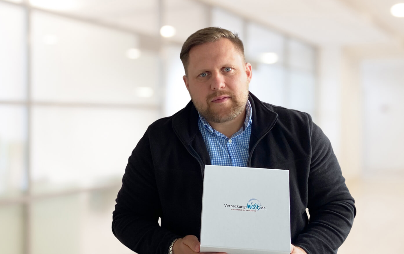 Ein Mitarbeiter aus dem Beratungsservice von Verpackungswelt hält einen bedruckten Karton in der Hand.