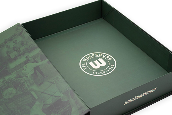 Geöffnete grüne Trikotbox mit VfL-Wolfsburg-Logo und Aufschrift „Jubiläumstrikot“